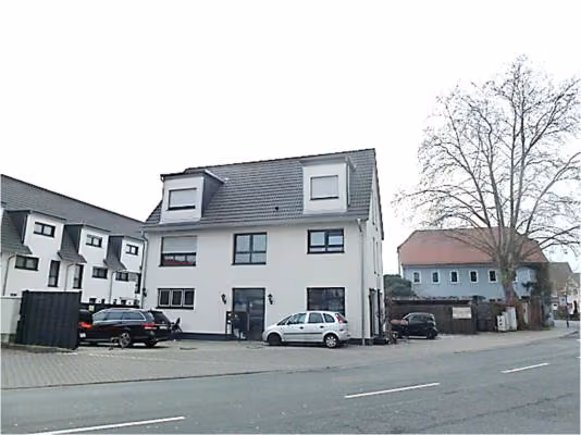 Zwangsversteigerung Einfamilienhaus in Raunheim – Straßenansicht des Objekts mit Gewerbeeingang im Erdgeschoss.
