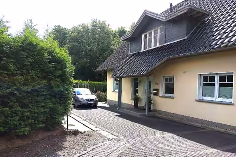 Zwangsversteigerung Einfamilienhaus in Menden – Nordansicht des Einfamilienhauses mit Hauseingang und Zufahrt.
