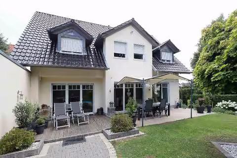 Zwangsversteigerung Einfamilienhaus in Menden – Gartenansicht des Wohnhauses mit Terrasse und ausgebautem Dachgeschoss.
