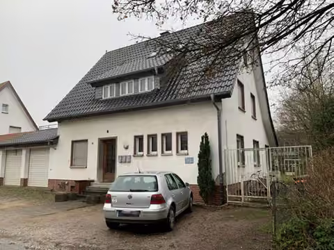 Zwangsversteigerung Einfamilienhaus in Rheda-Wiedenbrück, Rheda – Vorderansicht des Einfamilienhauses mit Vorplatz und Garagenanbau.
