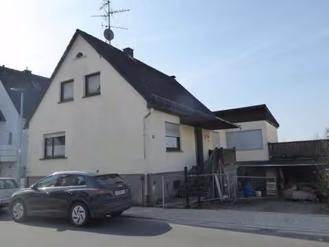 Zwangsversteigerung Einfamilienhaus in Mömbris, Daxberg – Schrägansicht von der Straße mit Garagen- und Hofbereich.