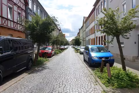 Zwangsversteigerung Mehrfamilienhaus in Mühlhausen – Straßenansicht mit Straßenraum und Parkbuchten.
