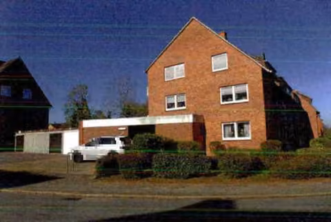 Zwangsversteigerung Mehrfamilienhaus in Itzehoe, Sude – Ostansicht des Gebäudes mit Giebelseite und Zufahrtsbereich.