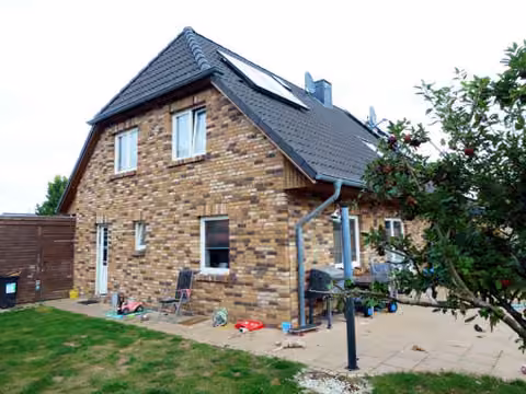 Zwangsversteigerung Eigentumswohnung in Geesthacht – Vorderansicht der Doppelhaushälfte mit Garten und Zuwegung.