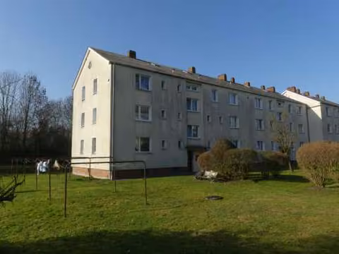 Zwangsversteigerung Eigentumswohnung in Lemwerder, Altenesch – Südostansicht des Mehrfamilienhauses Schlesische Straße 14 mit Hauseingang und Grünfläche.