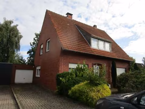 Zwangsversteigerung Einfamilienhaus in Lingen (Ems), Darme – Vorderansicht des Einfamilienhauses mit Vorgarten und Garage von der Straße aus.