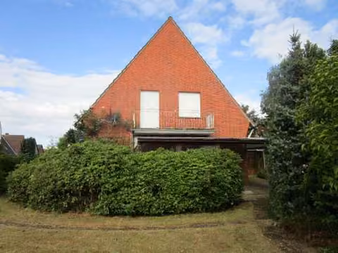 Zwangsversteigerung Einfamilienhaus in Lingen (Ems), Darme – Rückansicht des Gebäudes mit Gartenbereich und überdachter Terrasse.