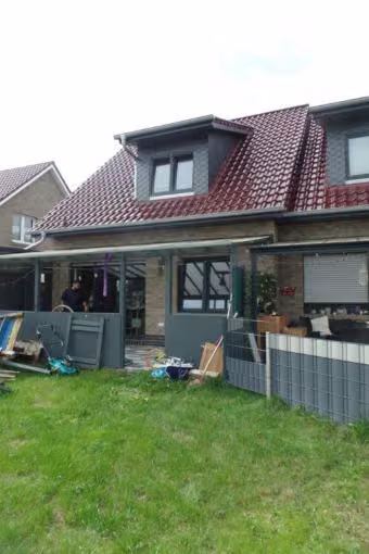 Zwangsversteigerung Doppelhaushälfte in Saterland, Scharrel – Rückansicht des Wohnhauses mit überdachter Terrasse und Garten