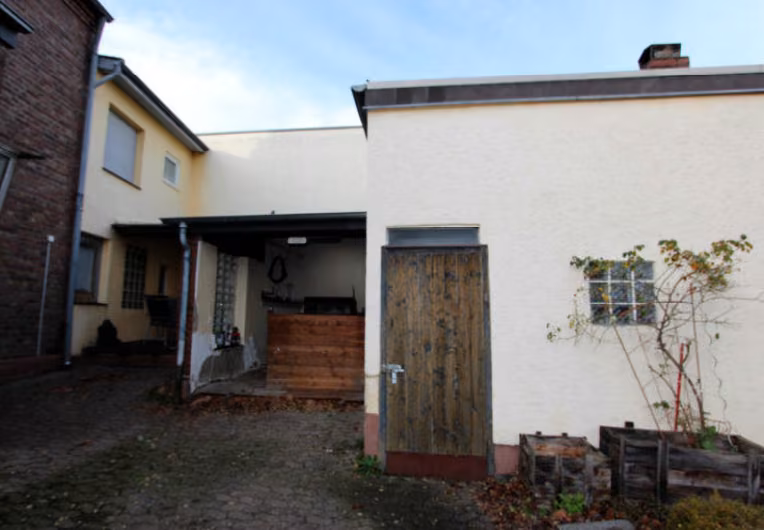 Zwangsversteigerung Einfamilienhaus in Brühl, Badorf – Rückwärtige Ansicht mit Hofbereich und Anbauten.