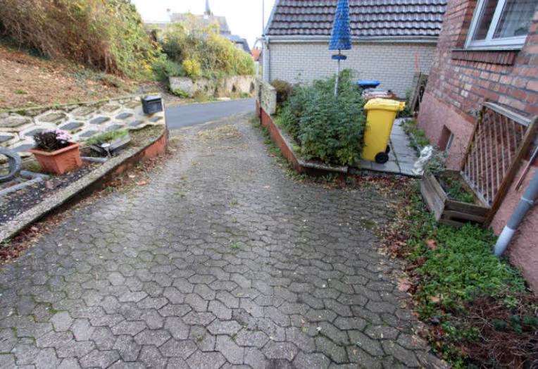 Zwangsversteigerung Einfamilienhaus in Brühl, Badorf – Gepflasterte Zufahrt und seitlicher Grundstücksbereich.