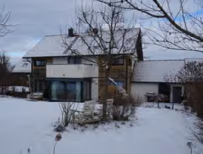Zwangsversteigerung Einfamilienhaus in Finsing – Südseite des Hauses mit Erker, Balkon und Holzverschalung im Schnee.