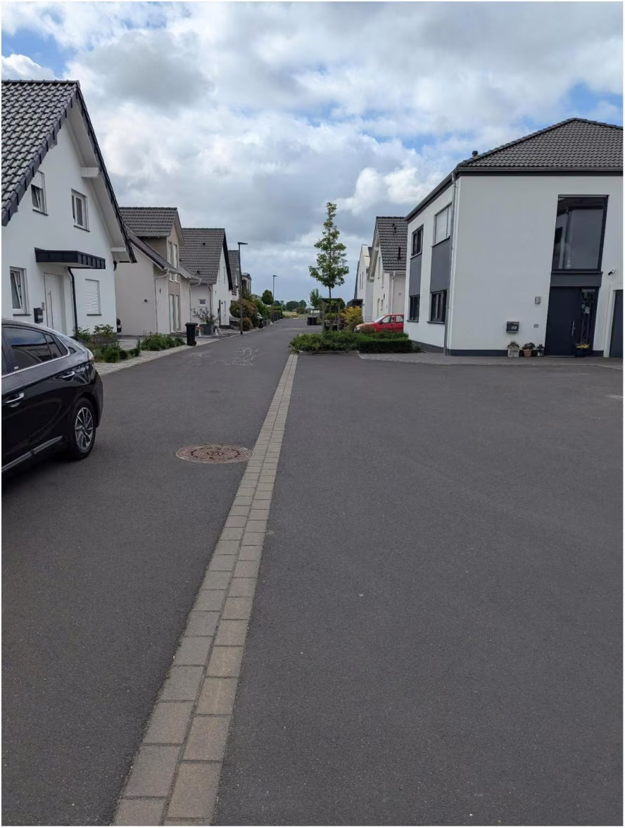 Zwangsversteigerung Einfamilienhaus in Zülpich, Wichterich – Blick in die Lommersumer Straße mit dem Haus rechts und Neubauten gegenüber.