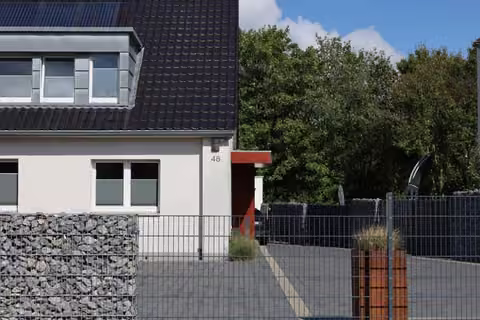 Zwangsversteigerung Einfamilienhaus in Rheine, Dorenkamp – Blick in die gepflasterte Einfahrt mit Tor und Solarpaneelen auf dem Dach.