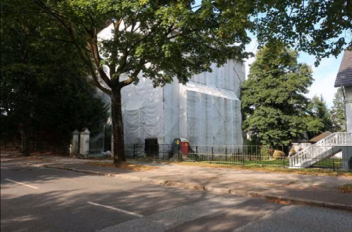 Zwangsversteigerung Mehrfamilienhaus in Bad Segeberg, Klein Niendorf – Seitenansicht des verhüllten Gebäudes mit Baumbestand Blickrichtung Westen.