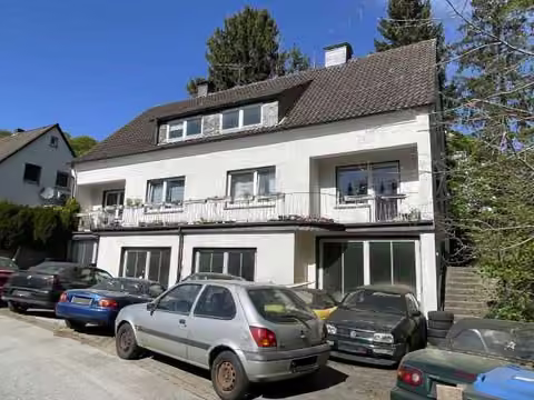Zwangsversteigerung Mehrfamilienhaus in Sprockhövel, Niedersprockhövel – Vorderansicht von rechts mit Fahrzeugen auf dem Hof.