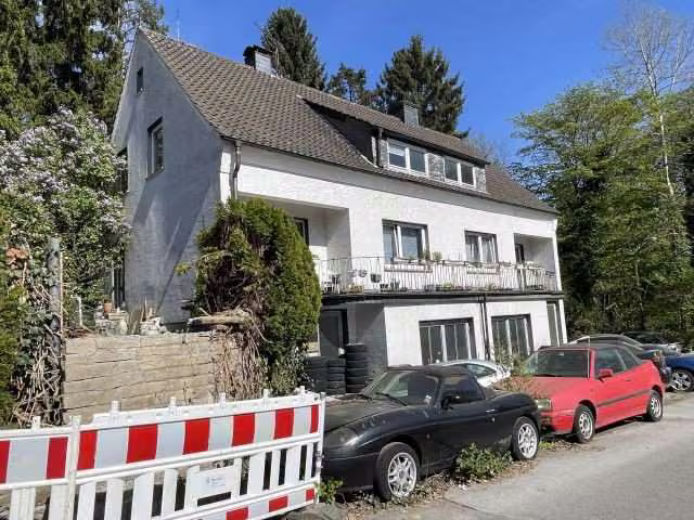 Zwangsversteigerung Mehrfamilienhaus in Sprockhövel, Niedersprockhövel – Vorderansicht von links mit Absperrung am Straßenrand.