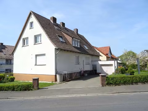 Zwangsversteigerung Zweifamilienhaus in Guxhagen, Ellenberg – Wohnhaus Ansicht von Südosten mit Zufahrt und Vorgarten.