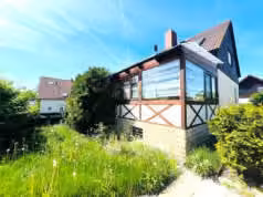 Zwangsversteigerung Einfamilienhaus in Bienstädt – Rück- und Seitenansicht mit Anbau und Wintergartenbereich.