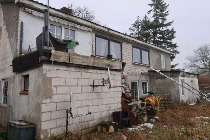 Zwangsversteigerung Einfamilienhaus in Schackendorf – Rückansicht und Giebelseite mit unverputztem Mauerwerk und unfertigen Anbauten.