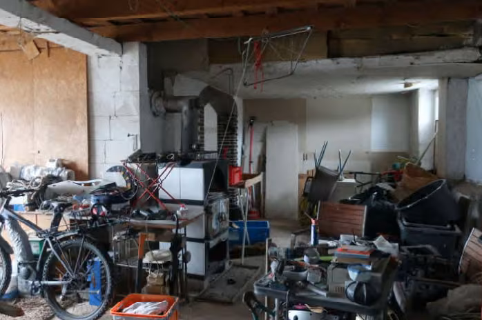 Zwangsversteigerung Einfamilienhaus in Schackendorf – Innenansicht des Erdgeschosses im unfertigen Rohbauzustand mit Unrat.