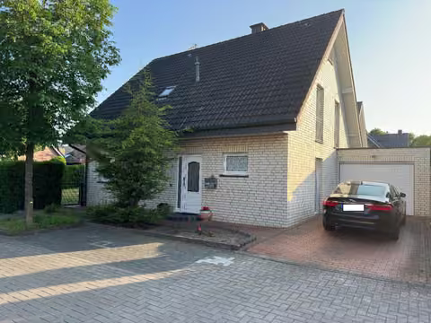 Zwangsversteigerung Einfamilienhaus in Rheine, Dutum – Frontansicht des Einfamilienhauses mit Hauseingang, Vorgarten und PKW-Stellplatz.