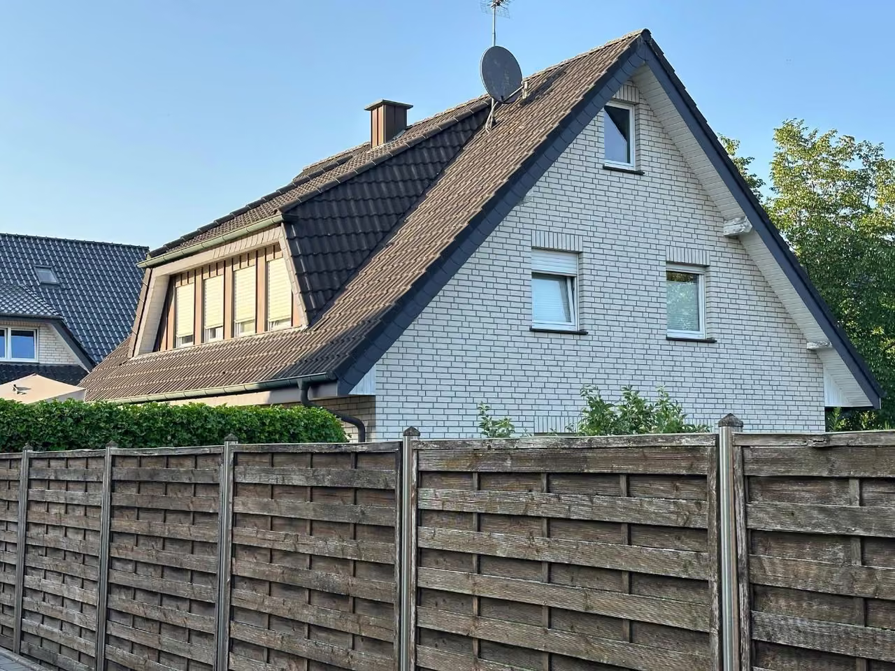 Zwangsversteigerung Einfamilienhaus in Rheine, Dutum – Giebelseite des Hauses mit Dachgaube und Gartenzaun.