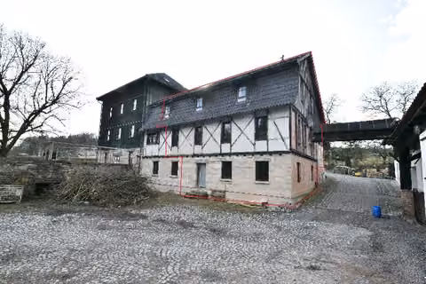 Zwangsversteigerung Eigentumswohnung in Schalkau, Bachfeld – Nordostansicht der Gebäudehälfte mit Hof- und Stellplatzbereich.