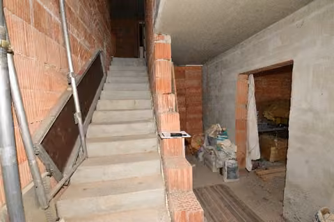 Zwangsversteigerung Eigentumswohnung in Schalkau, Bachfeld – Erdgeschoss mit Eingangsbereich und Treppenaufgang im Rohbau.