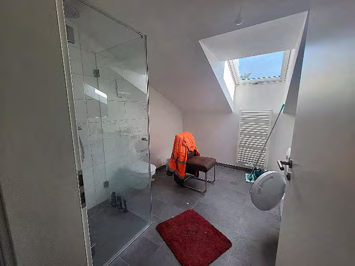Zwangsversteigerung Eigentumswohnung in Haar, Eglfing – Modernes Badezimmer mit bodengleicher Glasdusche und Dachflächenfenster.