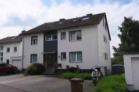 Zwangsversteigerung Mehrfamilienhaus in Niedernhausen – Vorderansicht des Mehrfamilienhauses mit Stellplatzbereich von Nordwesten.