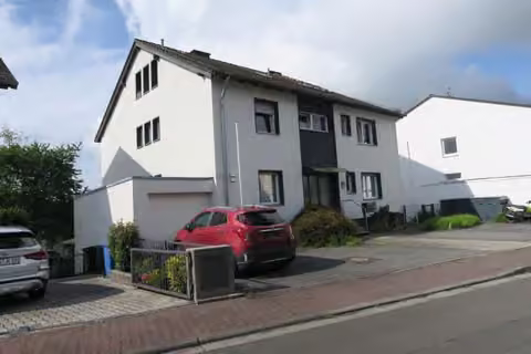 Zwangsversteigerung Mehrfamilienhaus in Niedernhausen – Seiten- und Frontansicht des Wohnhauses mit Garage von Nordosten.