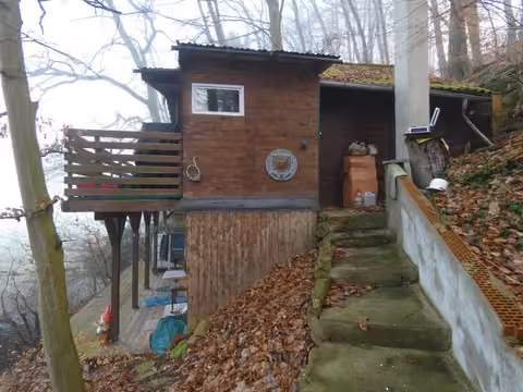 Zwangsversteigerung in Guxhagen, Büchenwerra – Südansicht des Wochenendhauses mit Außentreppe.