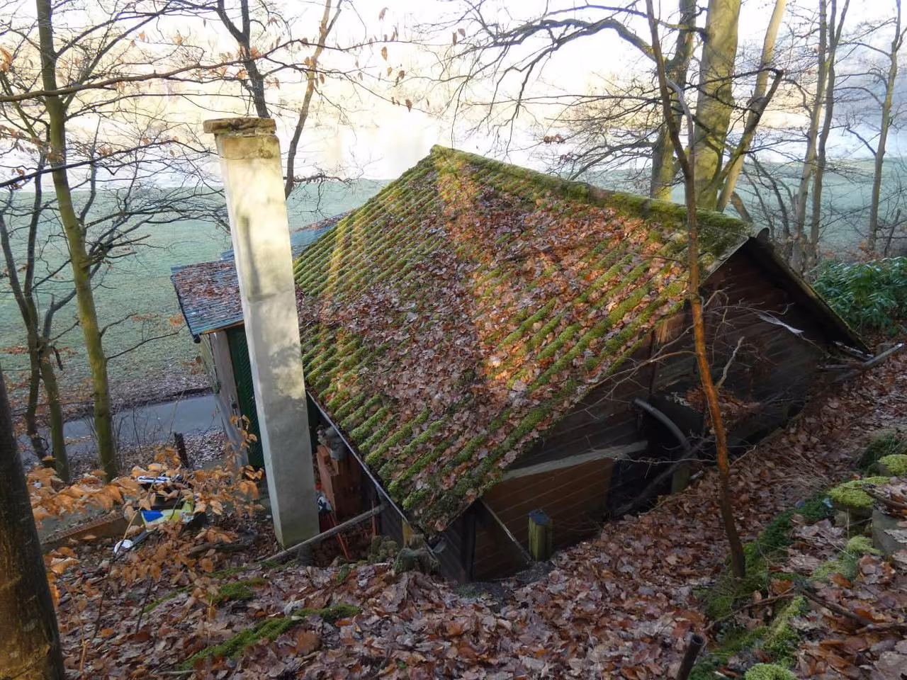 Zwangsversteigerung in Guxhagen, Büchenwerra – Ostansicht mit Dachfläche und Schornsteinkopf am Hang.