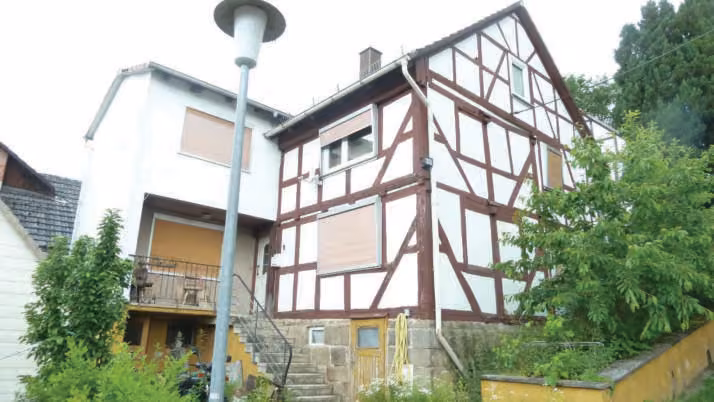 Zwangsversteigerung Einfamilienhaus in Breitenbach am Herzberg, Machtlos – Straßenseitige Ansicht des Gebäudes mit Eingangstreppe und Hanglage.