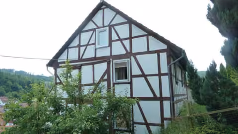 Zwangsversteigerung Einfamilienhaus in Breitenbach am Herzberg, Machtlos – Giebelseite des Fachwerkhauses mit Blick in die umgebende Landschaft.