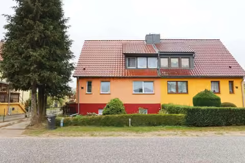 Zwangsversteigerung Einfamilienhaus in Lassan – Außenansicht der Doppelhaushälfte mit Vorgarten und Zuwegung.