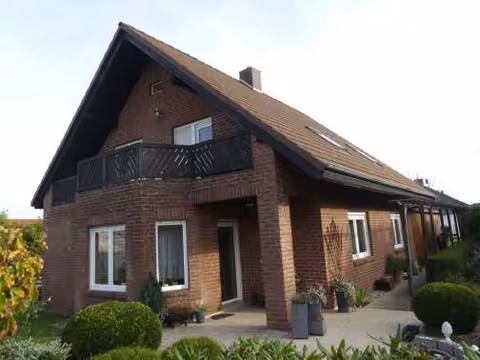 Zwangsversteigerung Einfamilienhaus in Heere, Klein Heere – Nordwestansicht des Einfamilienhauses mit überdachter Terrasse und Balkon.