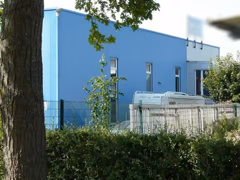 Zwangsversteigerung Grundstück in Geseke – Nordansicht des blauen Betriebsgebäudes.