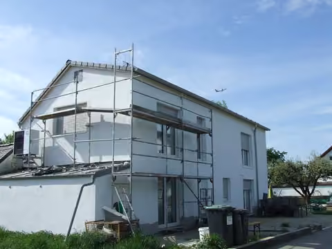 Zwangsversteigerung Doppelhaushälfte in Freising, Attaching – Südansicht der Doppelhaushälfte mit Baugerüst und Außenfassade.