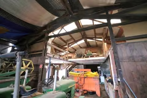 Zwangsversteigerung Landwirtschaft in Sulzbach – Innenansicht der westlichen Halle mit Dachkonstruktion und abgestelltem Inventar.
