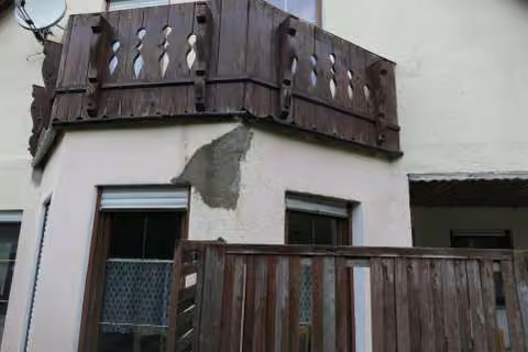 Zwangsversteigerung Einfamilienhaus in Schwarzenbach a. Wald – Giebelansicht mit Balkon und sichtbarem Fassadenwasserschaden am Erker.