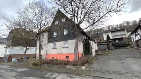 Zwangsversteigerung Einfamilienhaus in Eschenburg, Simmersbach – Vorderansicht des Wohnhauses mit Schiefergiebel und Eingangsbereich.