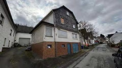 Zwangsversteigerung Einfamilienhaus in Eschenburg, Simmersbach – Vorderansicht des Wohnhauses an der Hornbergstraße mit Nebengebäude.