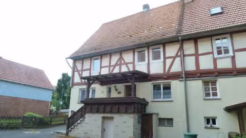 Zwangsversteigerung Doppelhaushälfte in Cornberg, Rockensüß – Rückseitige Ansicht der Doppelhaushälfte mit Eingangstreppe und Überdachung.