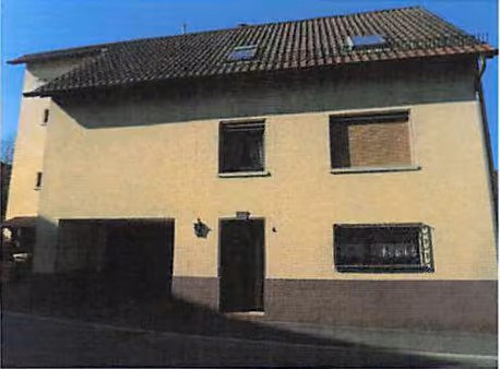 Zwangsversteigerung Mehrfamilienhaus in Epfenbach – Straßenansicht des Zweifamilienhauses mit Hauseingang und Garagentor.