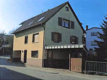 Zwangsversteigerung Mehrfamilienhaus in Epfenbach – Seitenansicht des Gebäudes mit Zufahrt und überdachtem Carport.