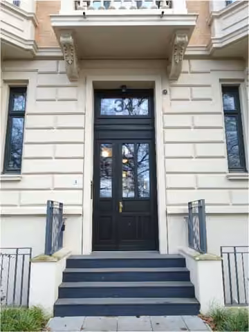 Zwangsversteigerung Eigentumswohnung in Hamburg, Uhlenhorst – Hauseingangsbereich und Treppenhaus mit historischem Stuck und Aufzug.