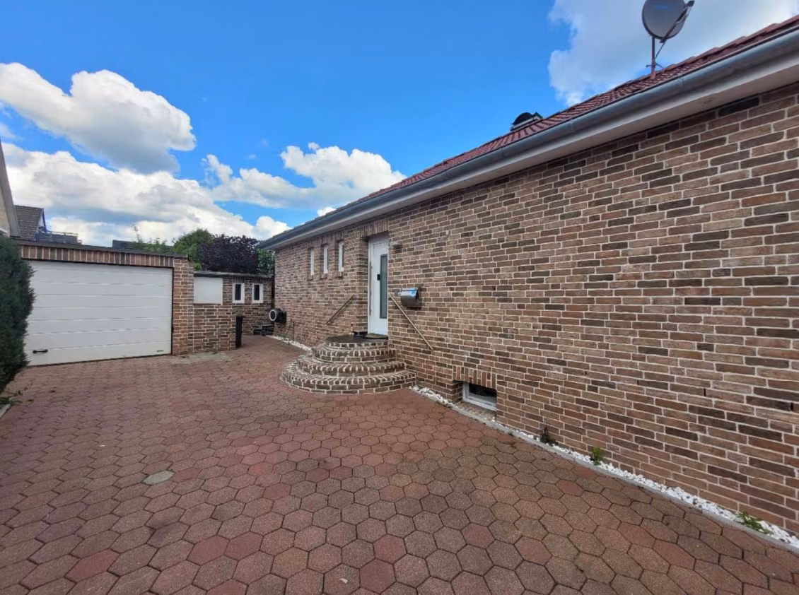 Zwangsversteigerung Einfamilienhaus in Deutsch Evern – Klinkerfassade und Eingangsbereich des Anbaus mit Garage im Hintergrund.