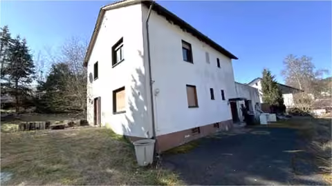 Zwangsversteigerung Zweifamilienhaus in Waldsolms, Hasselborn – Außenansicht des zweigeschossigen Wohnhauses mit Garten und Zufahrt.