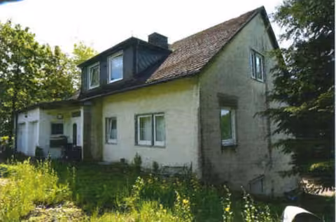 Zwangsversteigerung Mehrfamilienhaus in Brilon, Gudenhagen / Petersborn – Straßenansicht des Wohnhauses von Nordwesten mit Hanglage und Gartenbereich.